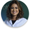 A picture of a smiling lady with brown hair, she is wearing a white coat