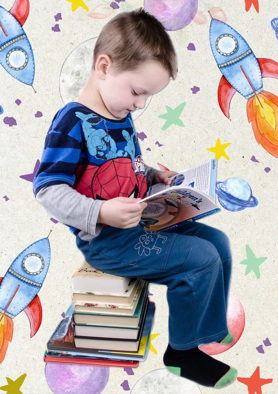  A small boy sitting on a bunch of books, he is reading a science book for kids